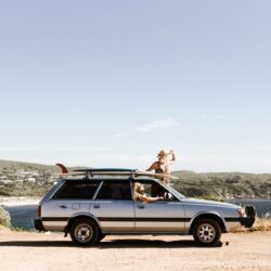 unrecognizable tourists looking out of car on rough road