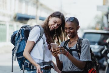 happy girls travelers with backpacks using mobile