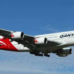 white and red qantas airplane fly high under blue and white clouds